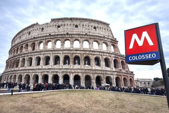 A metro train arriving at Colosseo station on Line B with the Colosseum visible through the exit