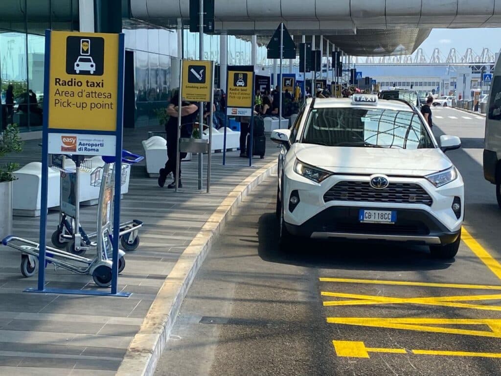 The white taxi rank sign and queue outside Fiumicino airport's arrivals hall